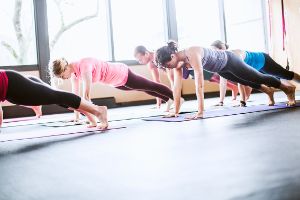 Frauen machen gemeinsam Liegestütze auf Matten in einem Raum.