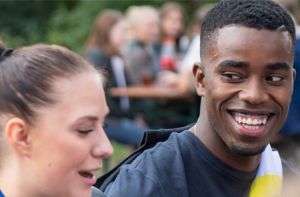 Auszubildende sitzen draußen am Tisch und unterhalten sich angeregt. Sie lachen dabei.