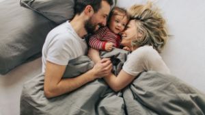 Eine Familie kuschelt im Bett.