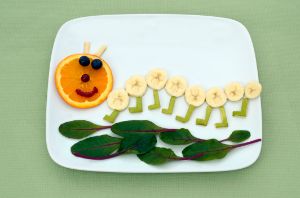 Raupe aus Obst und Gemüse auf einem Teller angerichtet.