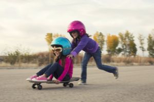 zwei Mädchen auf Skateboard in Bewegung.