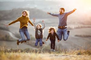 Eine Familie steht auf einer Wiese und springt in die Luft.