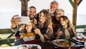 Eine Familie mit mehren Generation sitzt in der Natur und macht ein Foto von sich.