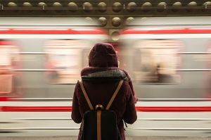 Eine Frau steht auf dem Bahnsteig, ein Zug fährt ein.