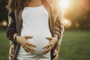 Eine schwangere Frau fasst sich an den Babybauch.